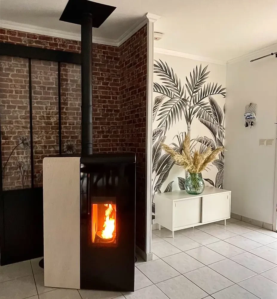 Intérieur chaleureux avec poêle à bois en fonctionnement, flammes vives visibles à travers la vitre, étincelles et particules incandescentes